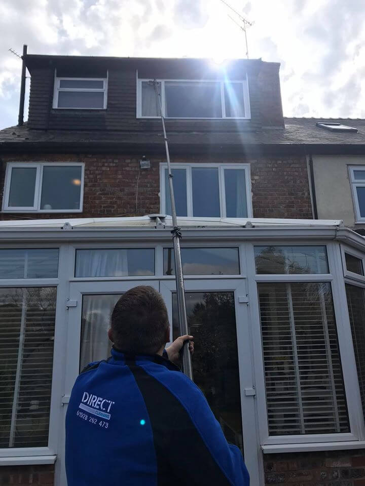 Man using reach and wash cleaning pole to clean windows